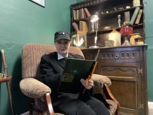 A lady story teller reading a book whilst smiling at the camera